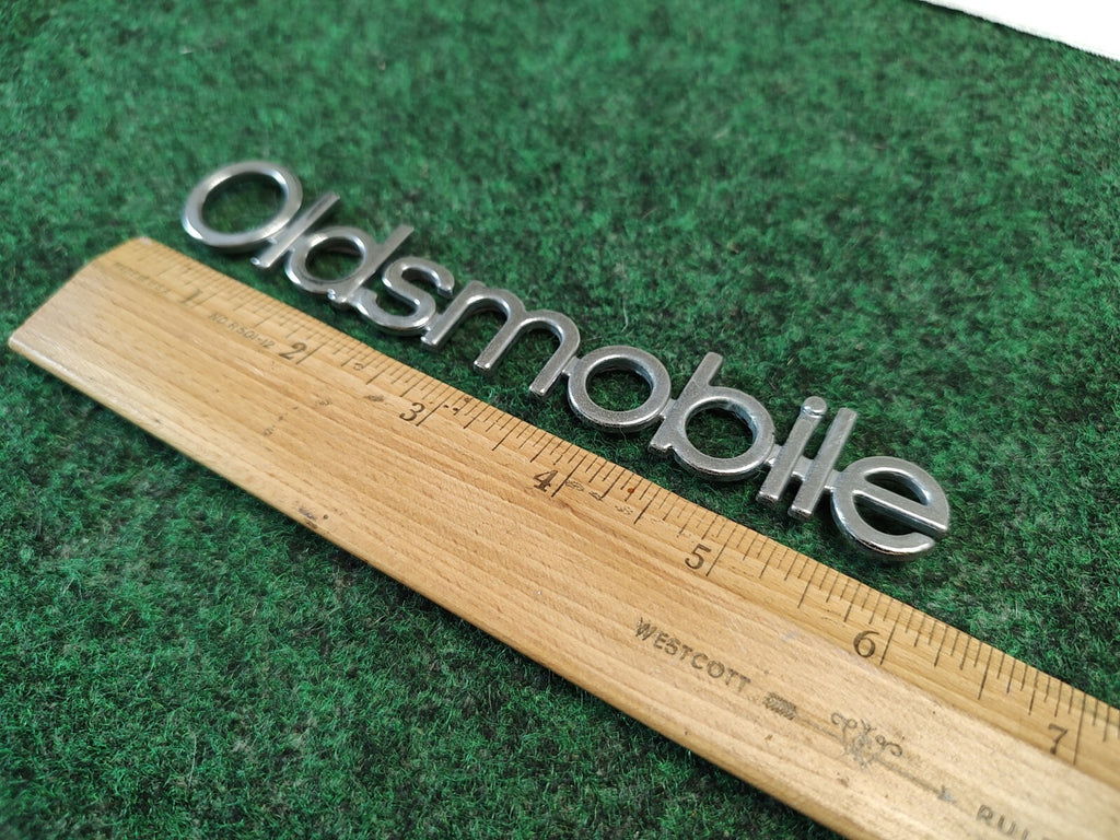Oldsmobile Cutlass Supreme NOS GM Rear Nameplate Emblem Chrome 16502255 4S7