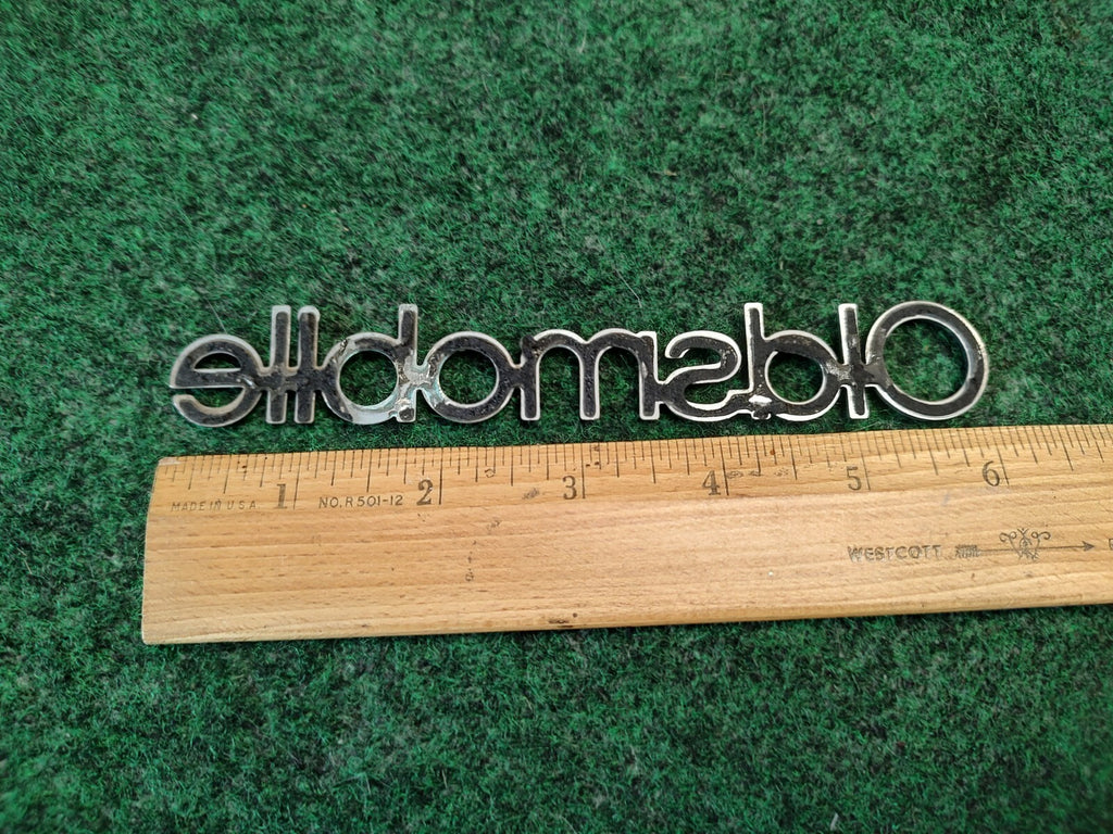 Oldsmobile Cutlass Supreme NOS GM Rear Nameplate Emblem Chrome 16502255 4S7